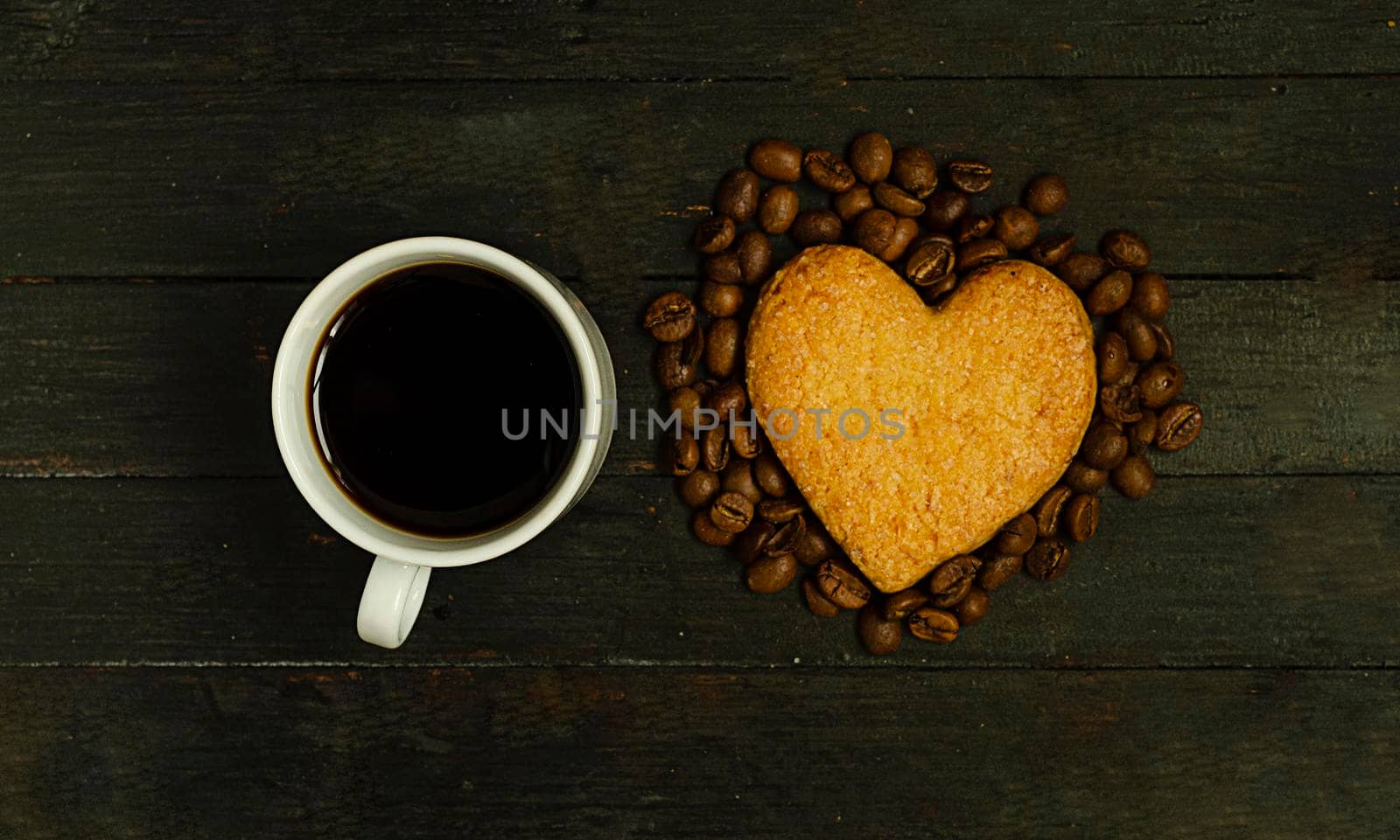 A cup of coffee and love cookie with coffee beans on wooden surface,top view.Valentine day holiday