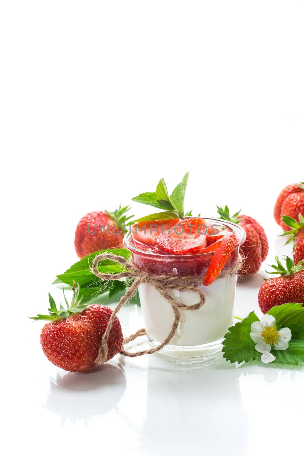 sweet homemade yogurt with strawberry jam and fresh strawberries in a glass, isolated on white background.