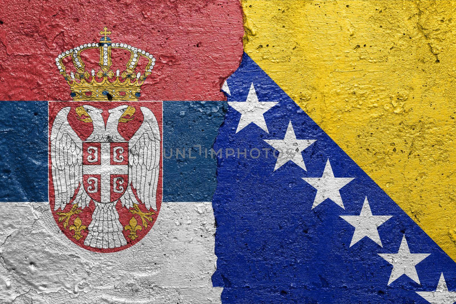 Serbia and Bosnia and Hercegovina - Cracked concrete wall painted with a Serbian flag on the left and a Bosnian flag on the right stock photo by adamr