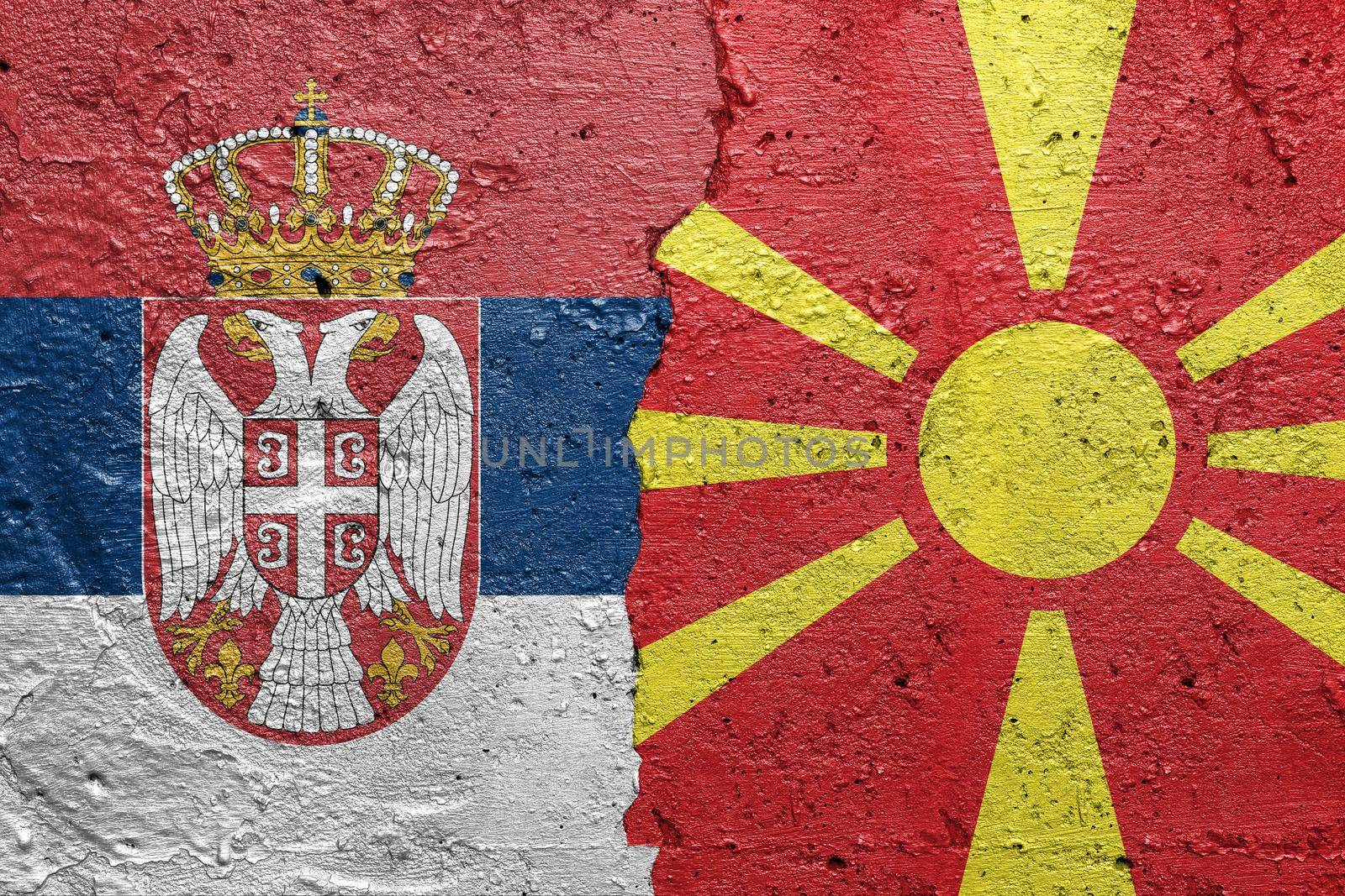 Serbia and North Macedonia - Cracked concrete wall painted with a Serbian flag on the left and a Macedonian flag on the right stock photo by adamr