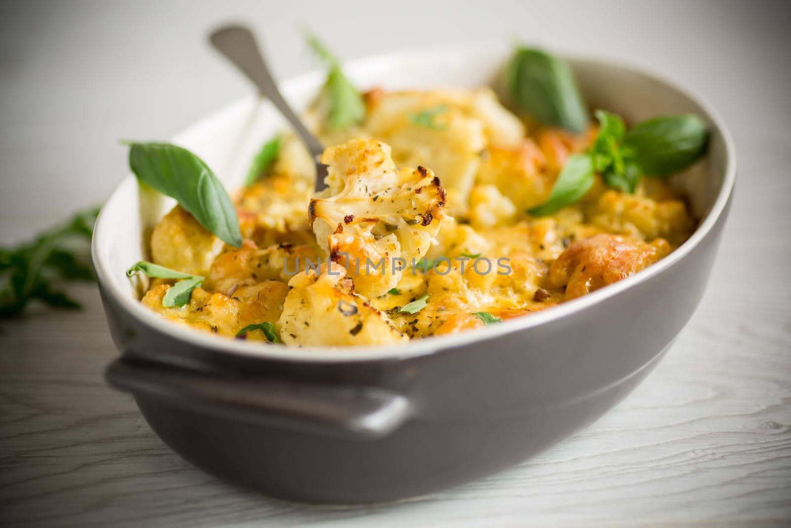 baked cauliflower with vegetables and cheese and scrambled eggs in a ceramic dish