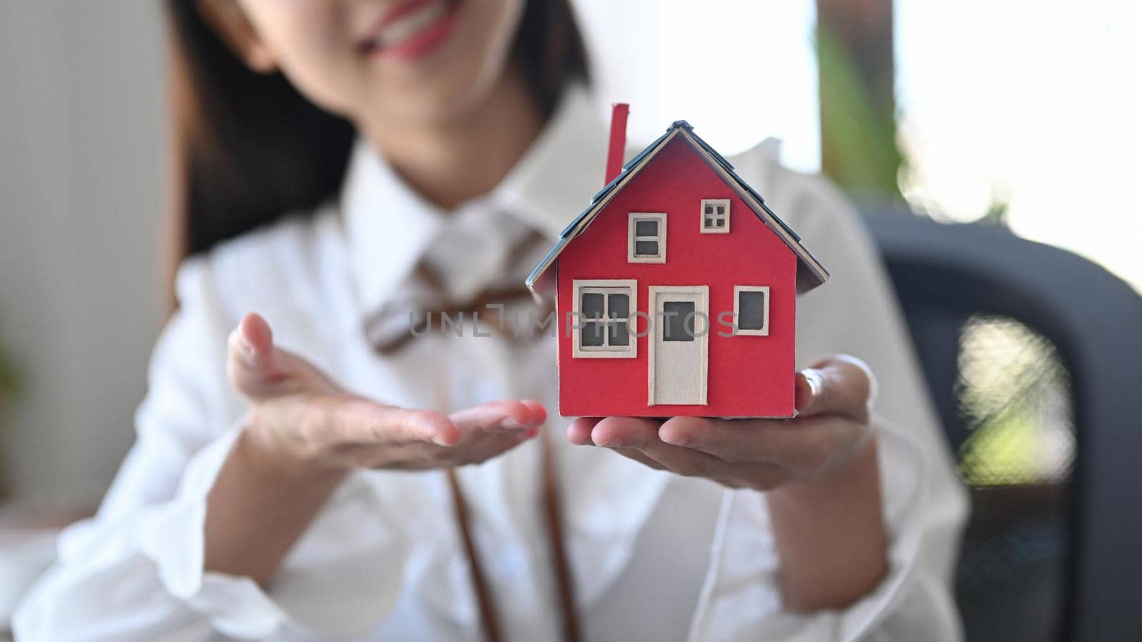 Woman holding and showing house model. Real estate investment and insurance concept.
