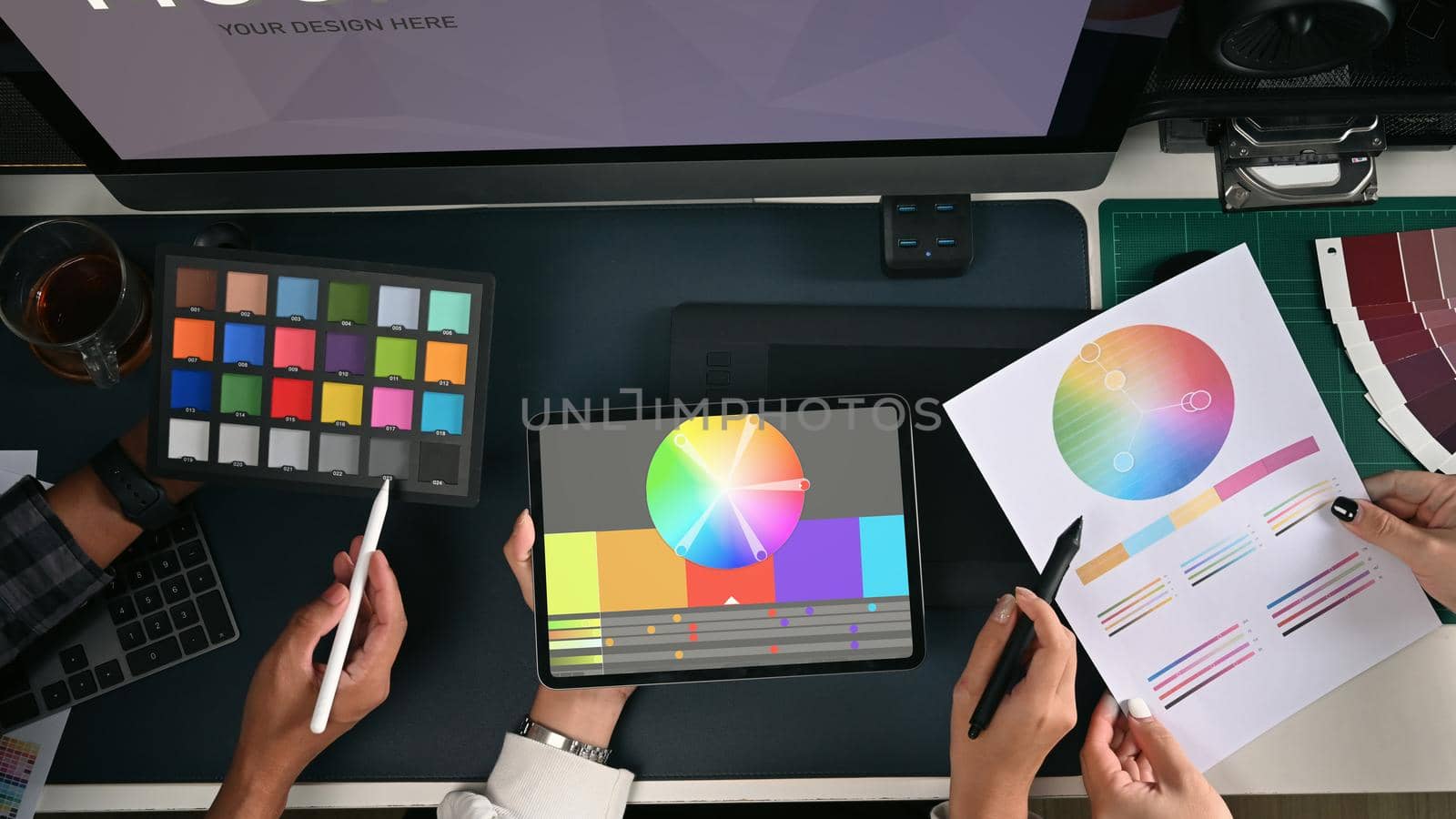 Team of creative designers working with modern devices and color swatch samples at design studio. by prathanchorruangsak