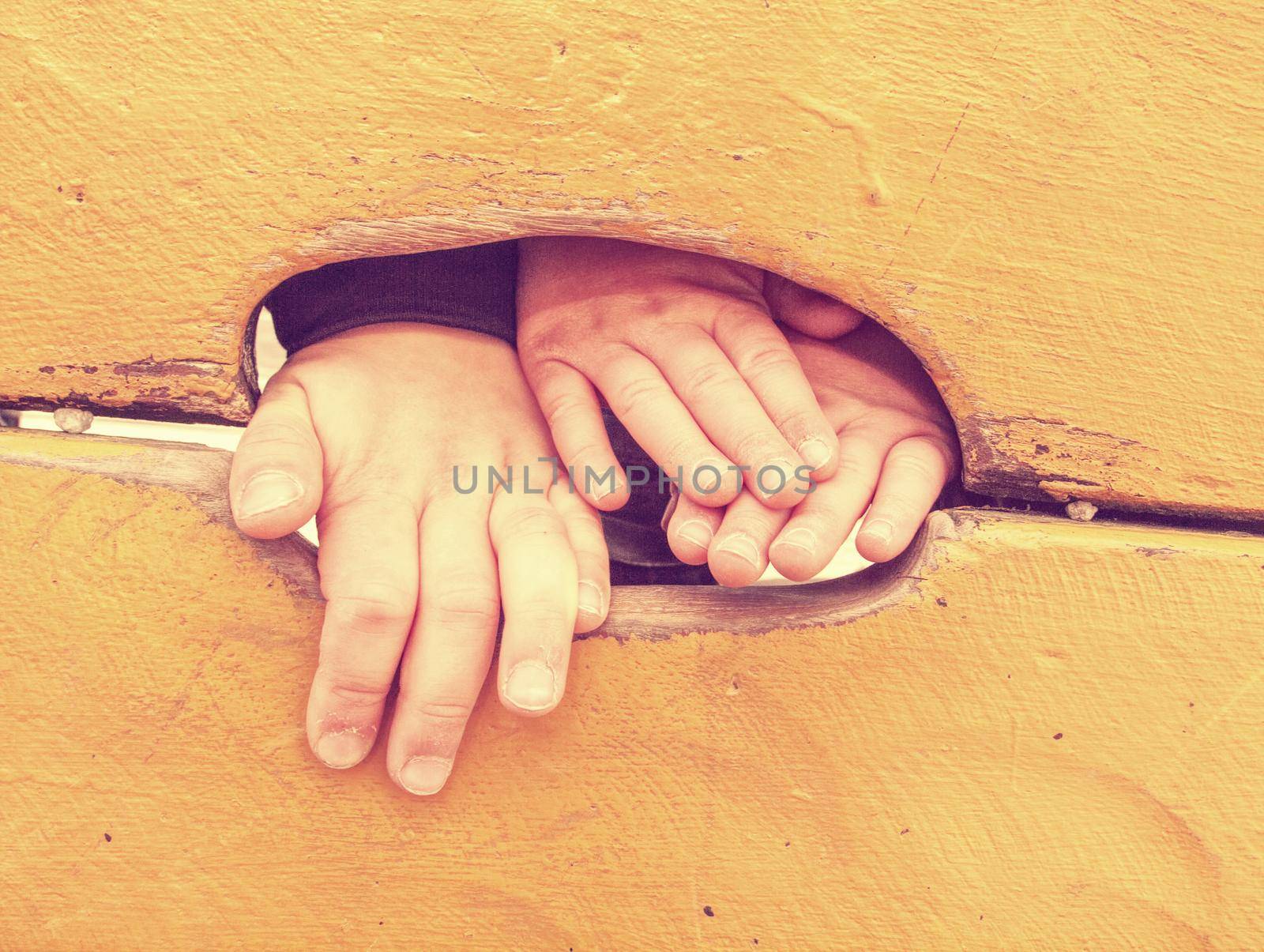 Kid climbing hand in hole of outdoor climbing wooden wall. Selective focus on the hand. 