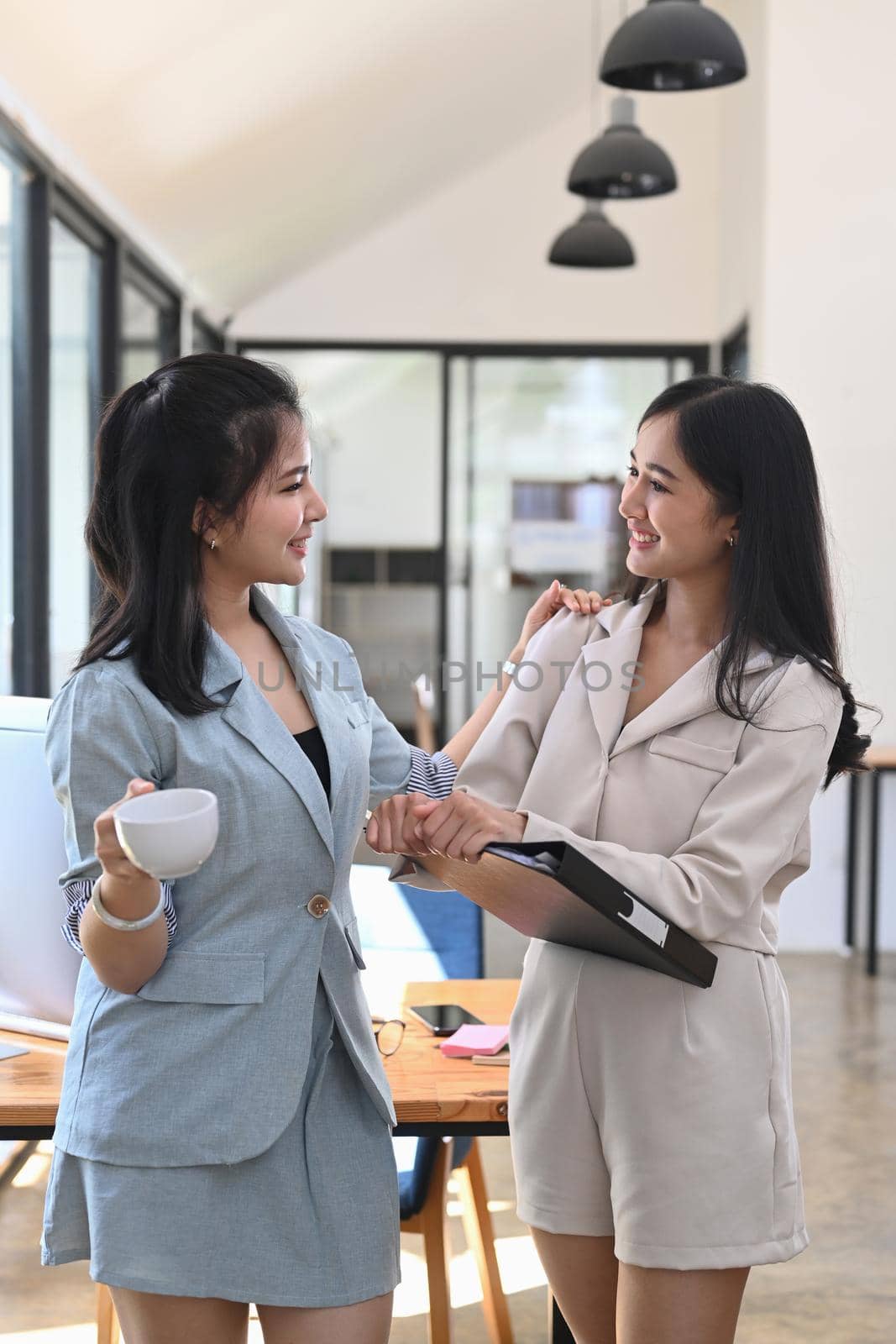 Two beautiful businesswoman talking each other during coffee break. by prathanchorruangsak