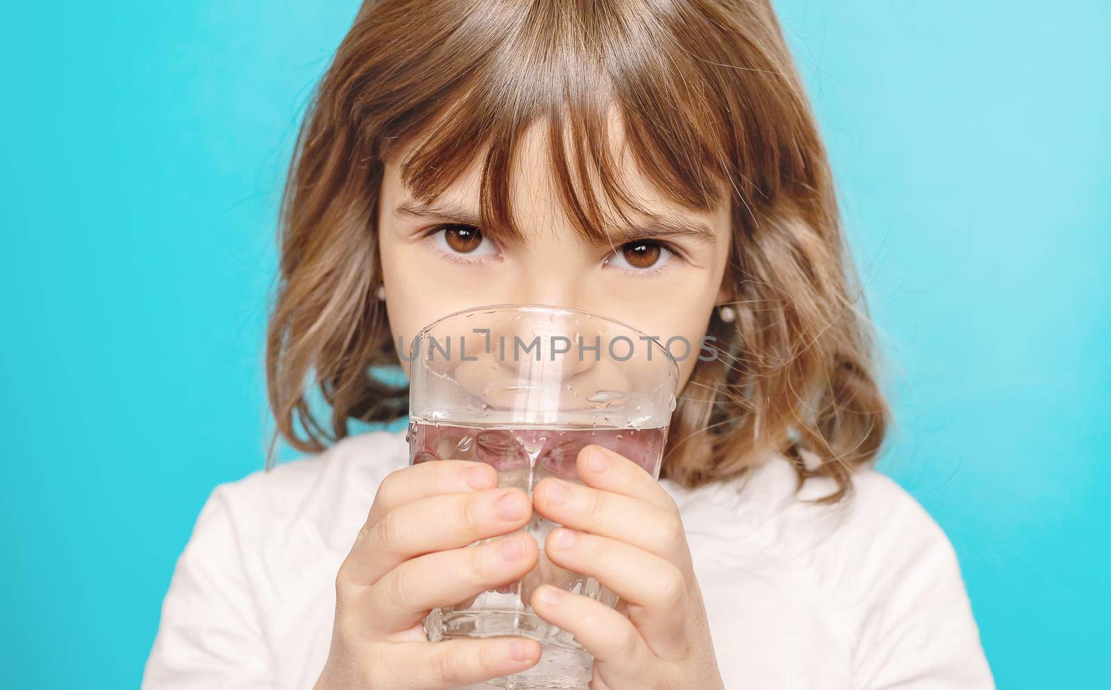 Child girl drinks water from a glass. Selective focus.