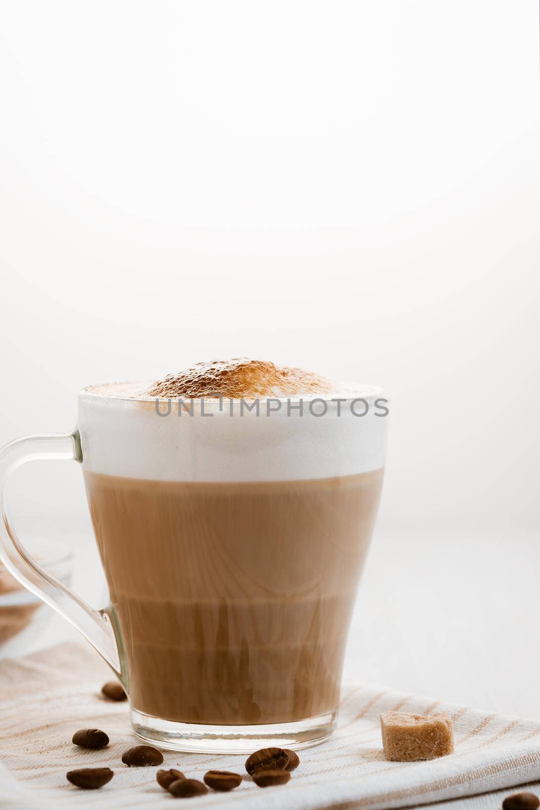 Latte coffee poured in layers with froth and a crispy chocolate top on a light kitchen table. Vertical image with copy space by galsand