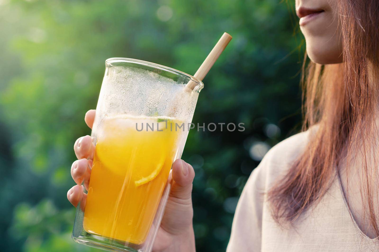 Girl holding glass with fresh orange summer cocktail, close-up, selective focus.