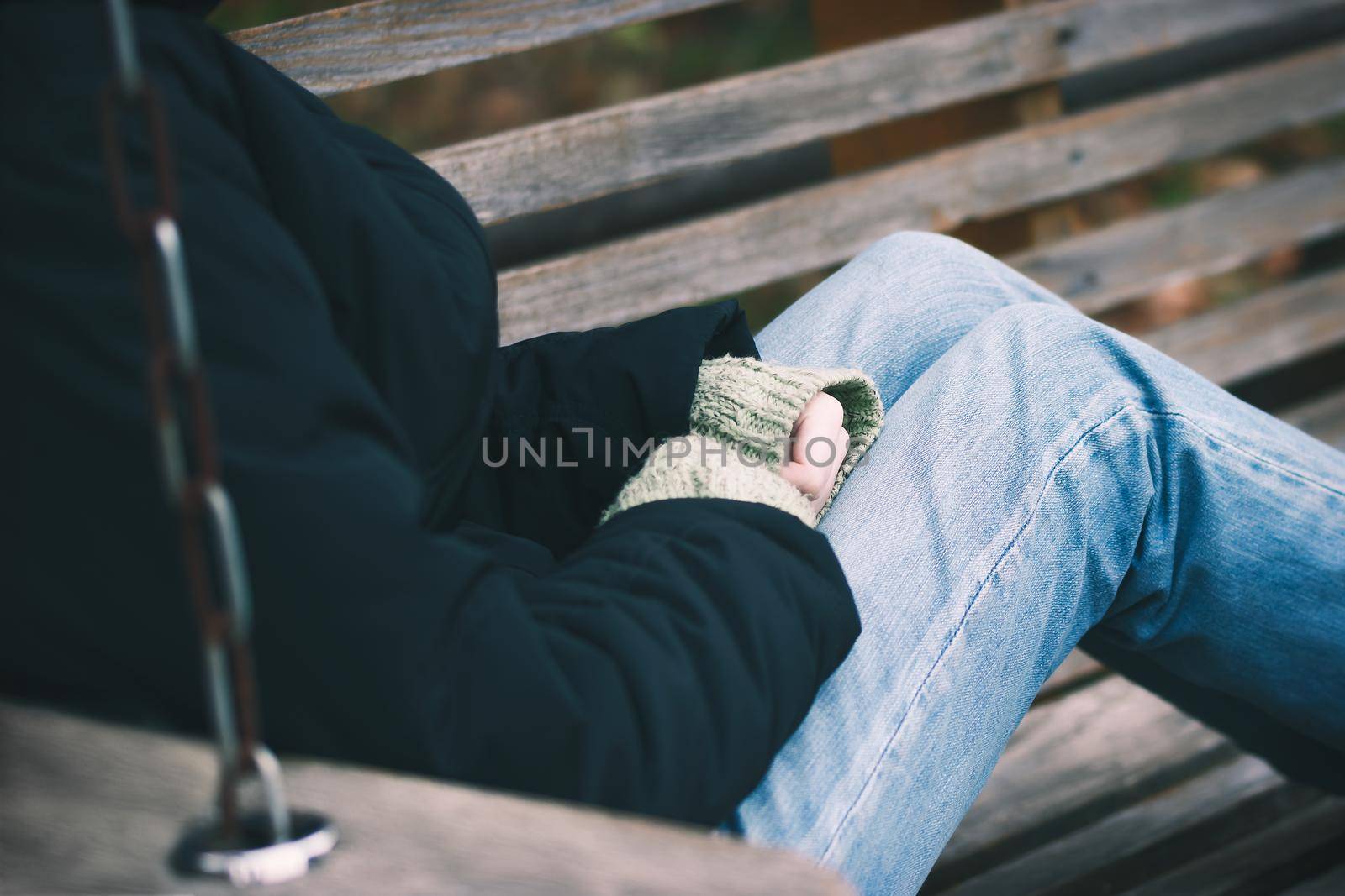 Lonely girl sitting on a bench in autumn park.