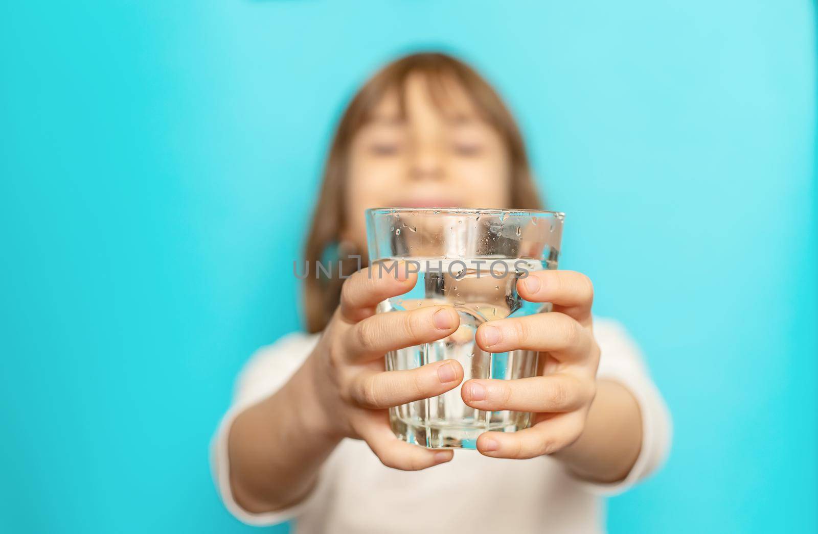 Child girl drinks water from a glass. Selective focus.