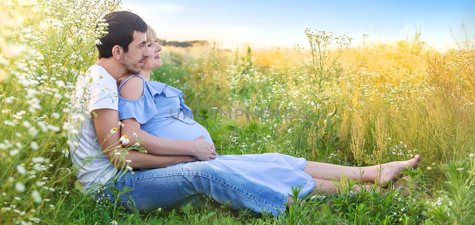 man hugs belly of a pregnant woman on nature. Selective focus. by yanadjana