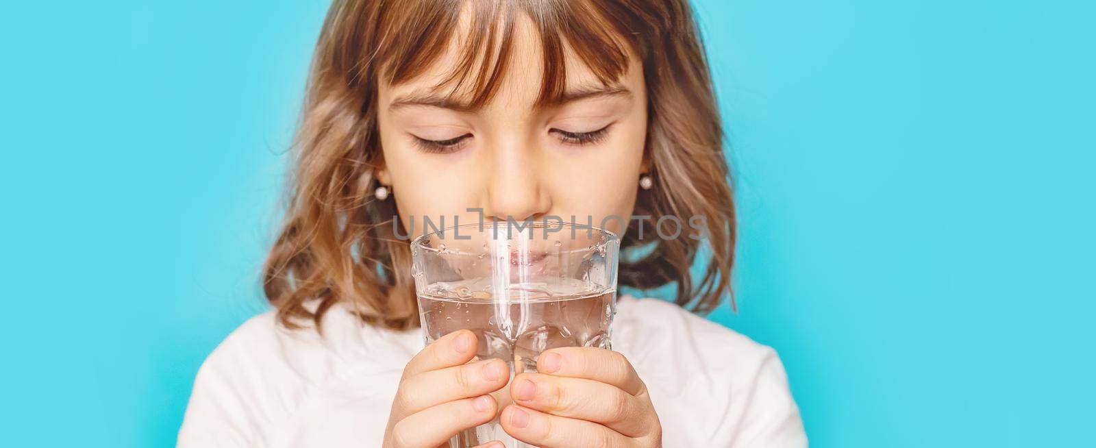 Child girl drinks water from a glass. Selective focus.