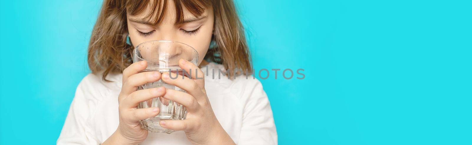 Child girl drinks water from a glass. Selective focus. by yanadjana