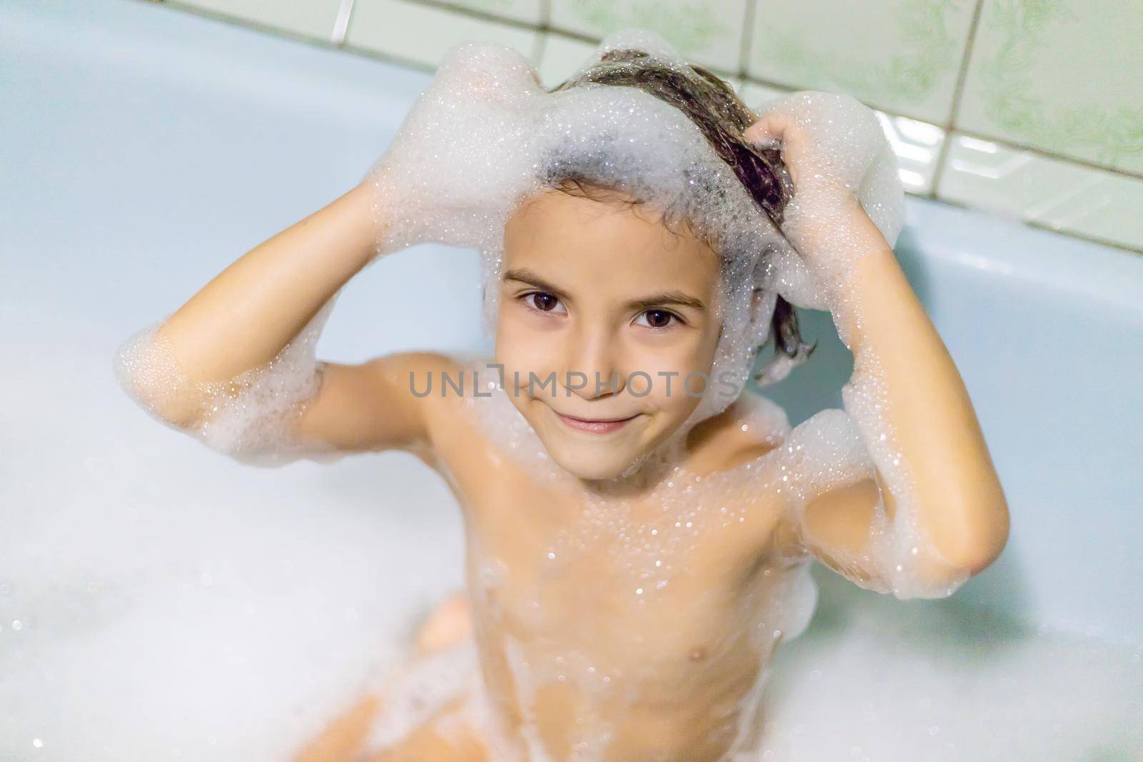 The child bathes in a bathtub soapy water. Selective focus.