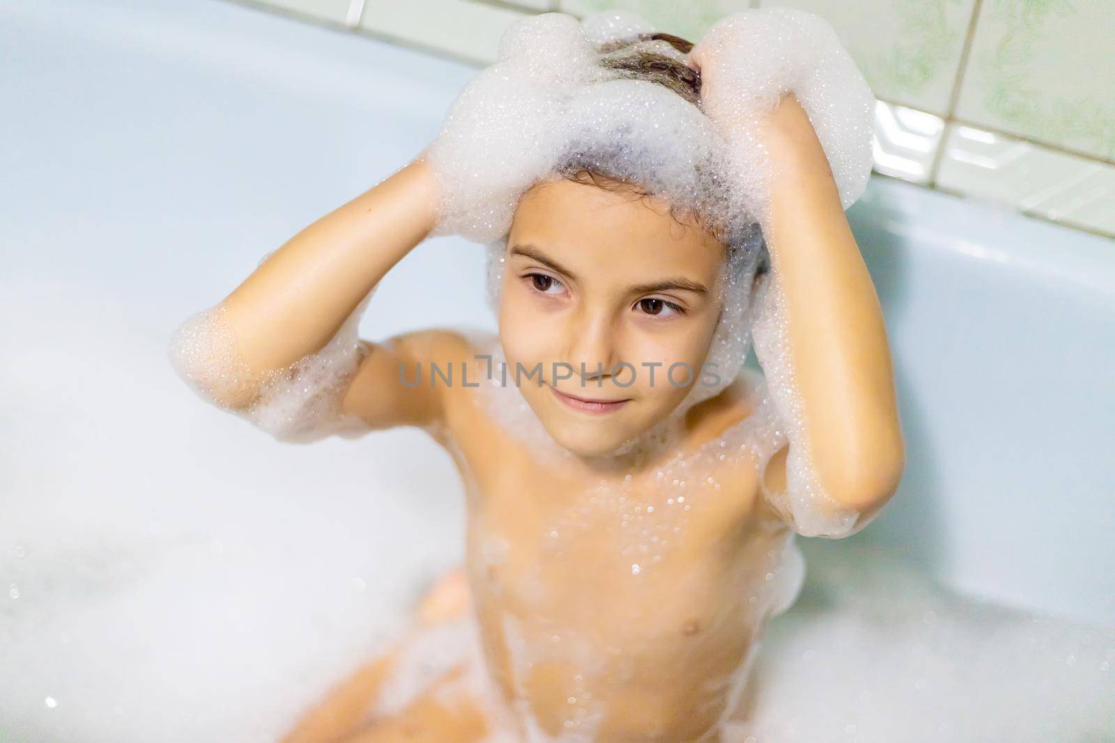 The child bathes in a bathtub soapy water. Selective focus.
