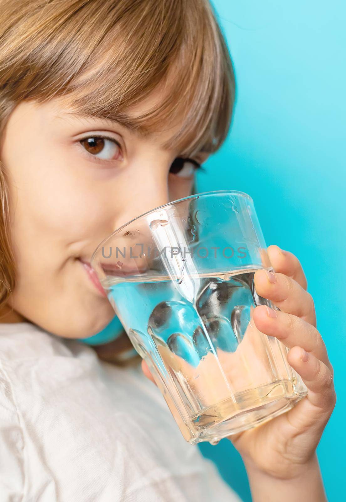 Child girl drinks water from a glass. Selective focus.