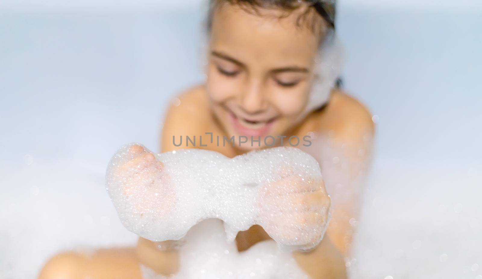 The child bathes in a bathtub soapy water. Selective focus.