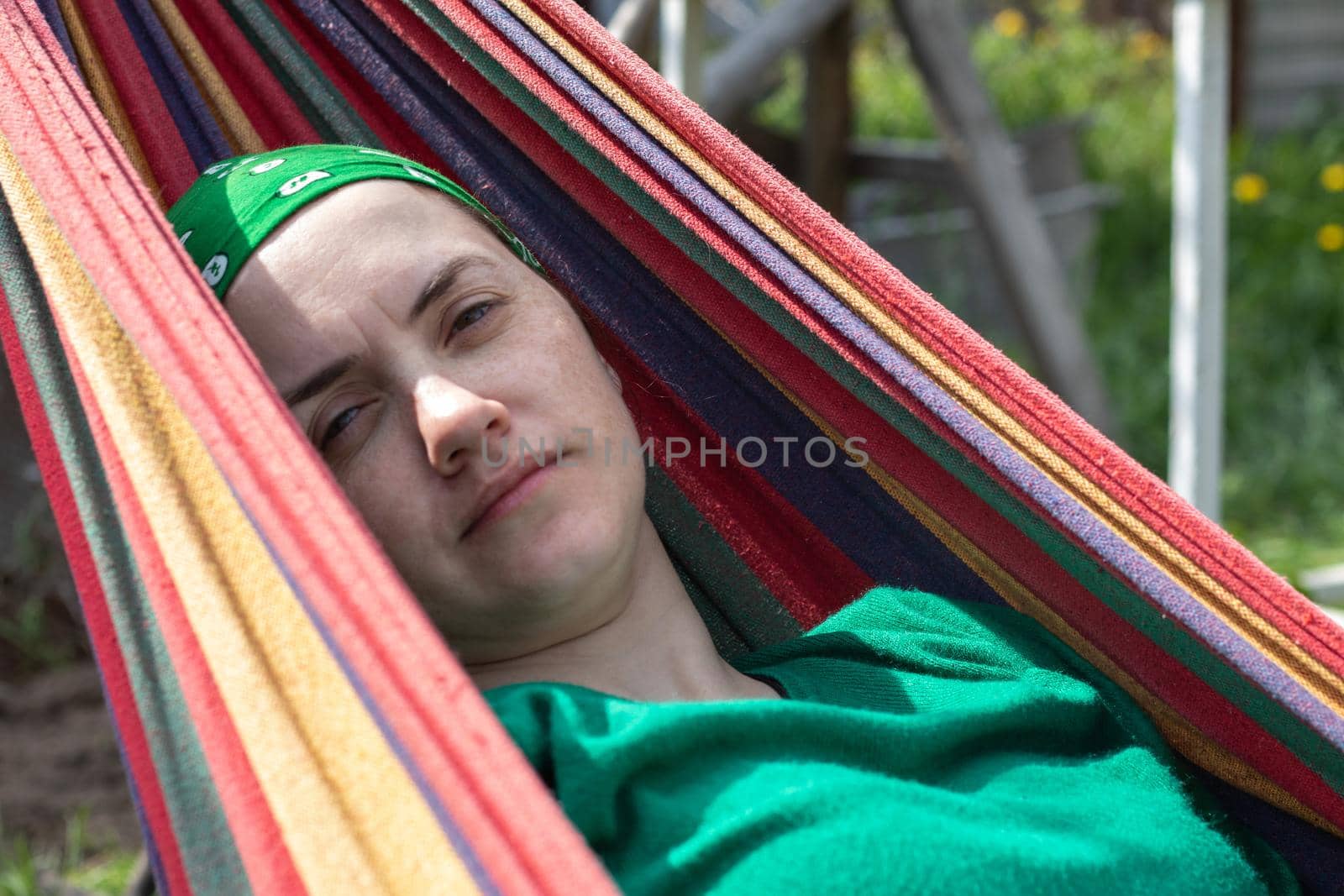 A woman of Caucasian appearance lies in a hammock outside in a park. Relaxing in a hammock, relaxing in a summer garden