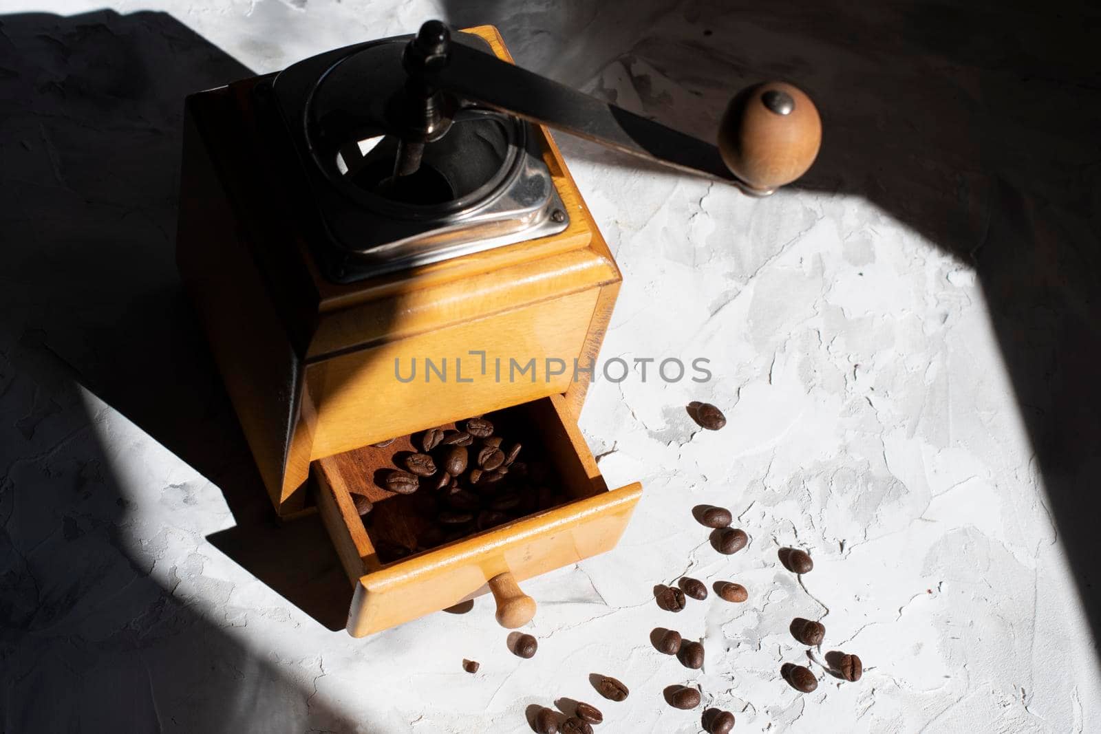 whole roasted coffee beans in the drawer of a vintage wooden coffee grinder in the sun, close up. High quality photo