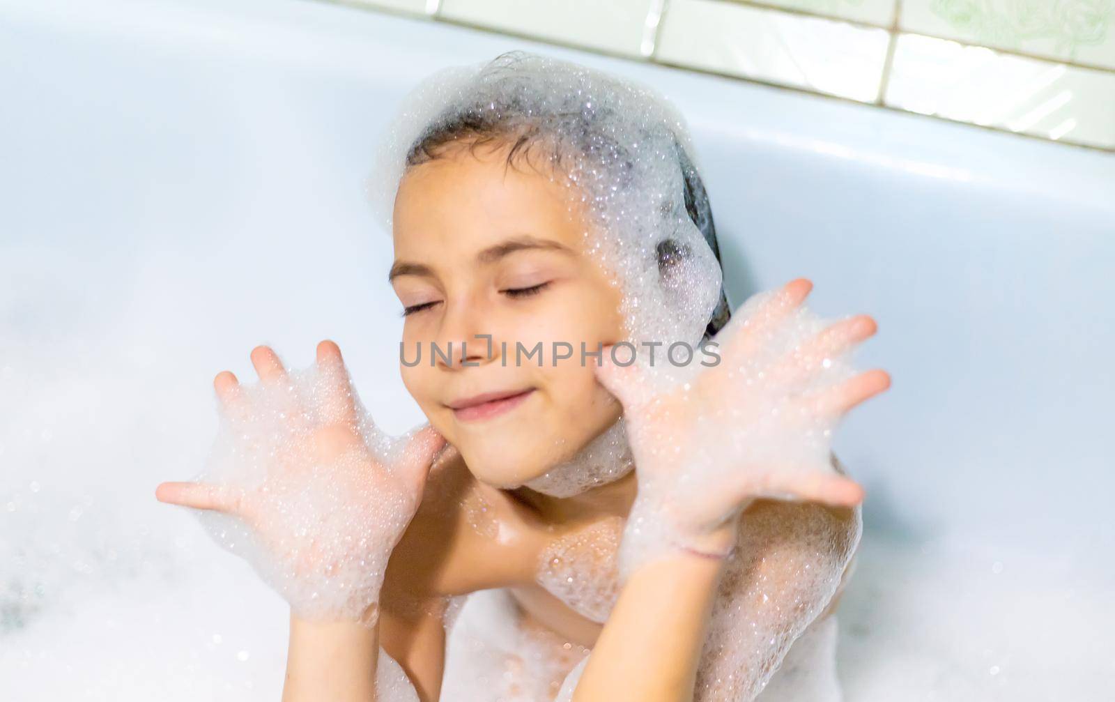 The child bathes in a bathtub soapy water. Selective focus.