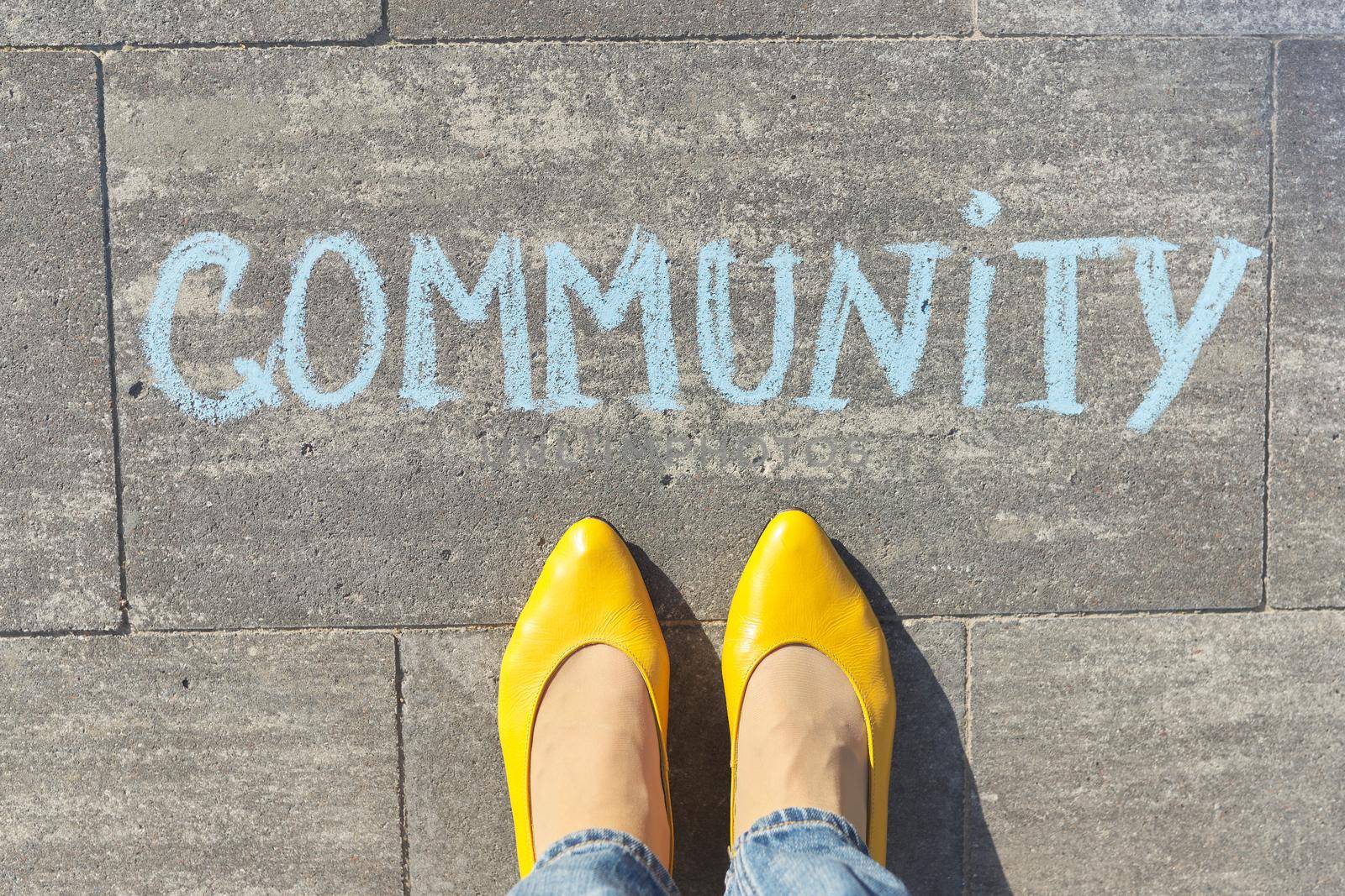 Community concept, top view on woman legs and text written in chalk on gray sidewalk by VH-studio