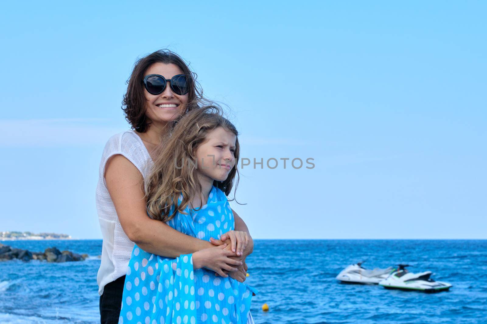 Happy mom and daughter kid hugging together on beach, copy space. Family, vacation, happiness, childhood, mother and child communication