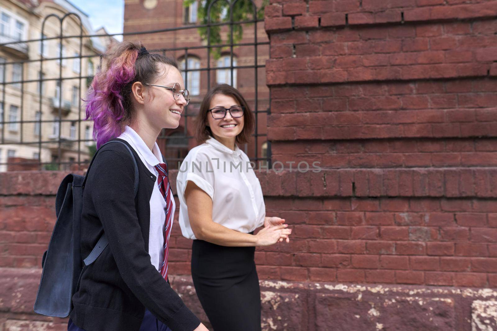 Happy smiling mother and daughter teenager student walking and talking together outdoor, copy space