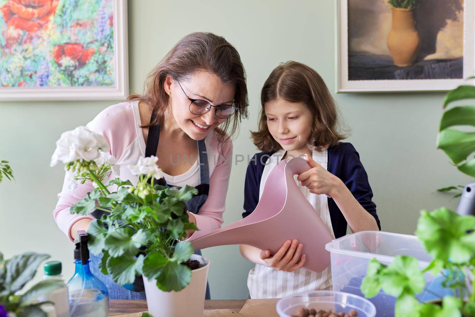 Mother and daughter kid together take care of indoor plants in pots, girl watering flower from watering can. Hobbies and leisure, care, family, houseplant, home potted friends concept