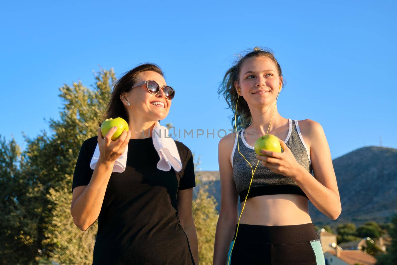 Athletic healthy family lifestyle, happy mother and teenage daughter eating apples by VH-studio