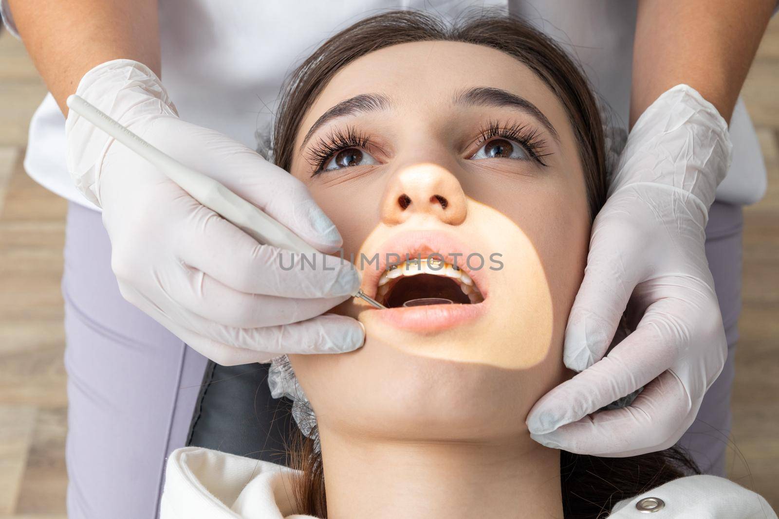 Dentist examining patient teeth with mirror in dentist clinic by Mariakray