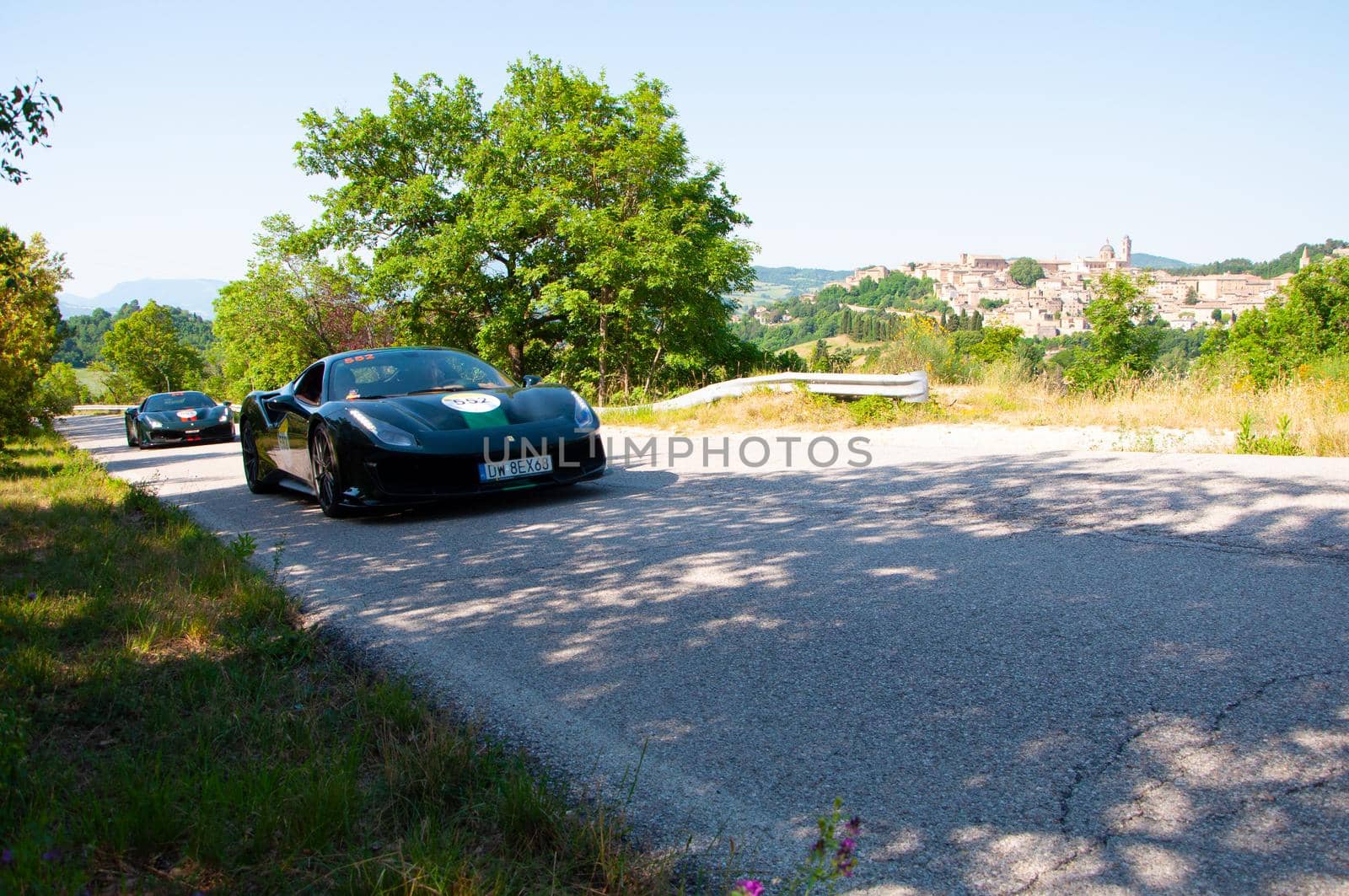 URBINO, ITALY - JUN 16 - 2022 : LAD SCAPE URBINO FERRARI TRIBUTE Ferrari 488 Pista IN an old racing car in rally Mille Miglia 2022