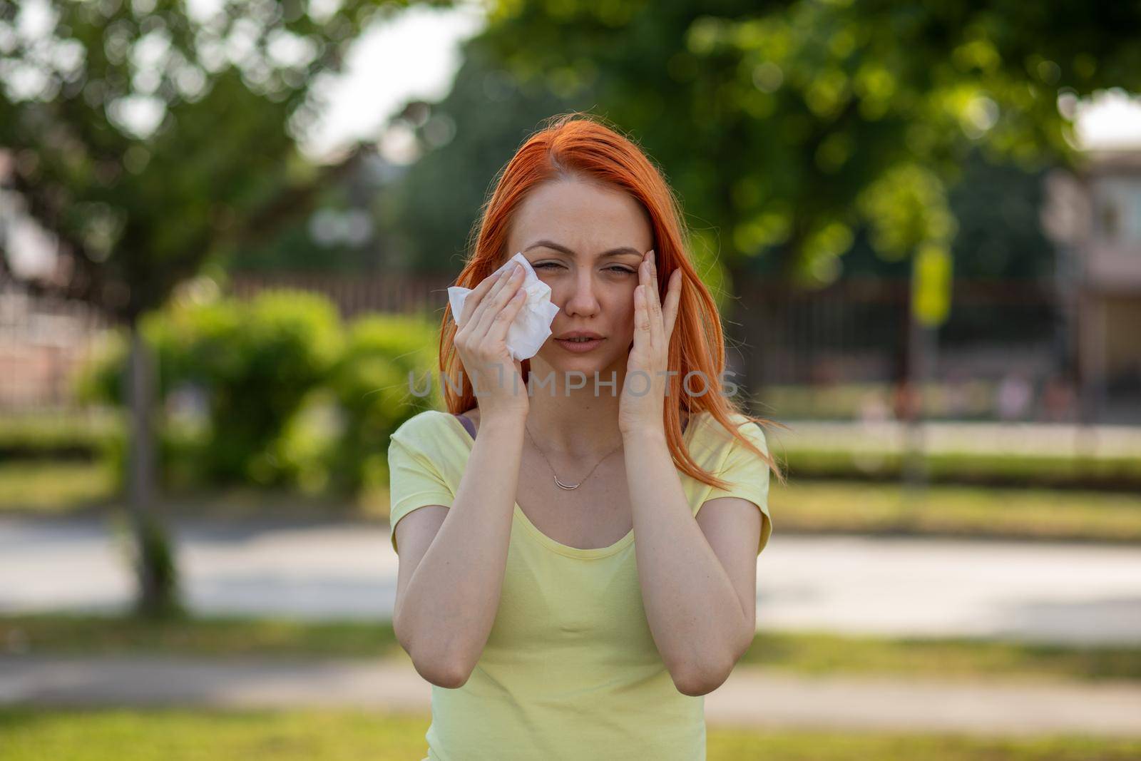 Young redhair woman sneezing. Pollen Allergy symptoms by adamr