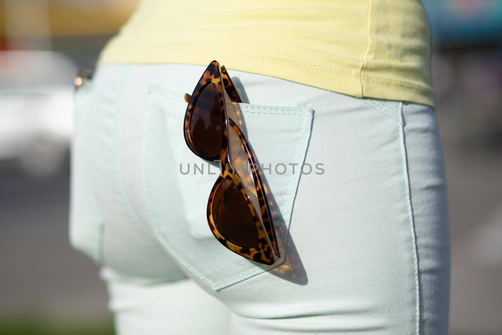 Fashionable Retro style Sunglasses in the back pocket of female jeans by adamr
