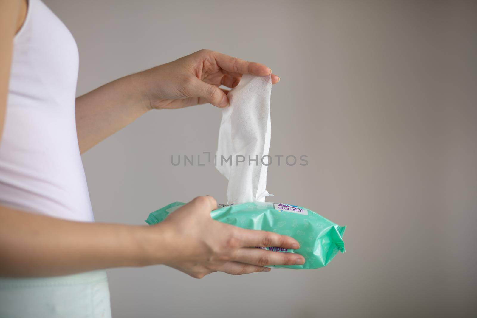 Woman taking wet baby wipes from the packaging - skin care, hygiene procedure and prevention of infectious diseases
