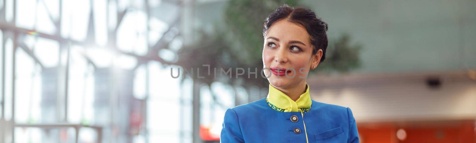 Female flight attendant standing in airport terminal by Yaroslav_astakhov