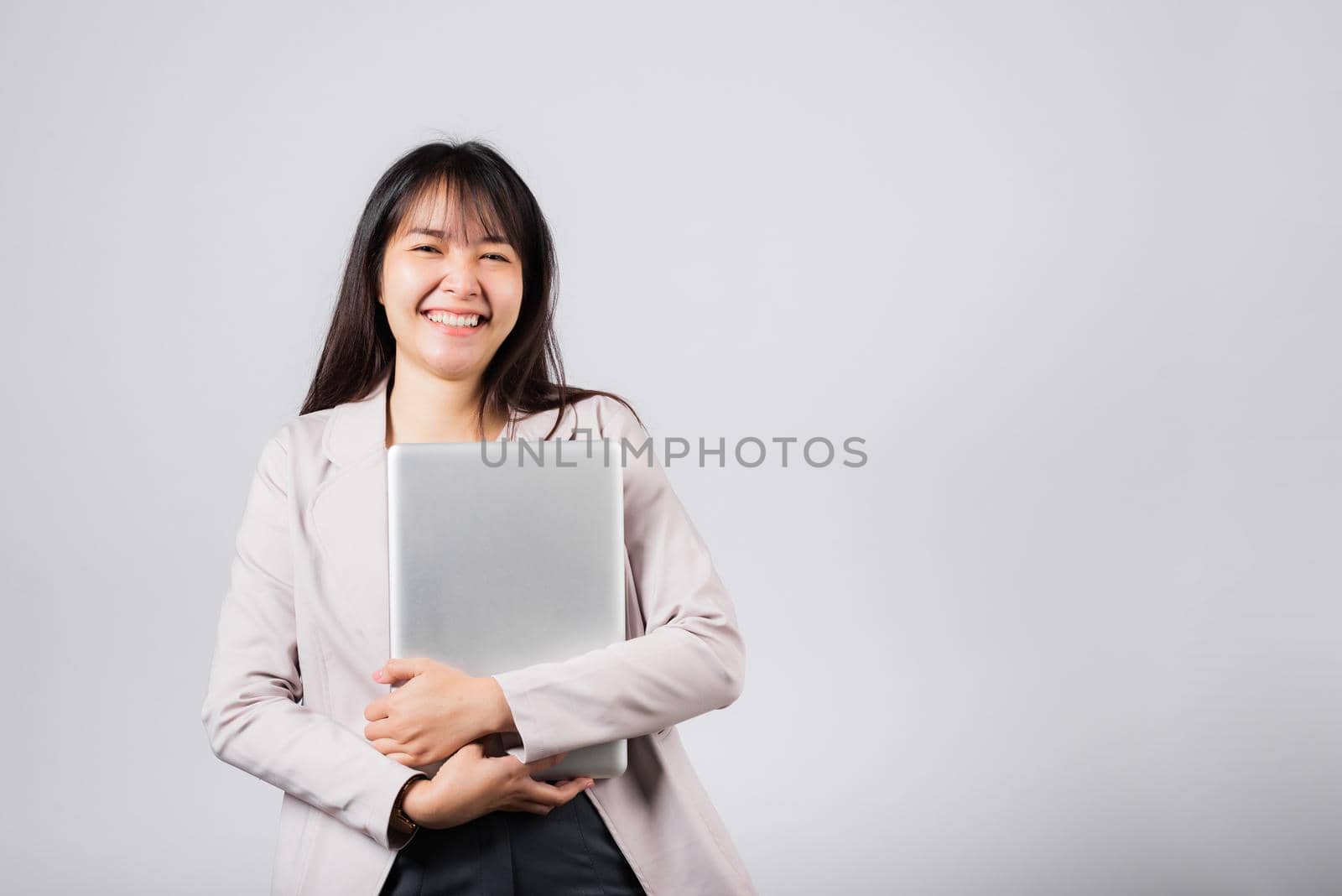 Front view woman smiling confident smiling holding closed laptop, Portrait excited happy Asian young female person hugging close cover computer device studio shot isolated on white background