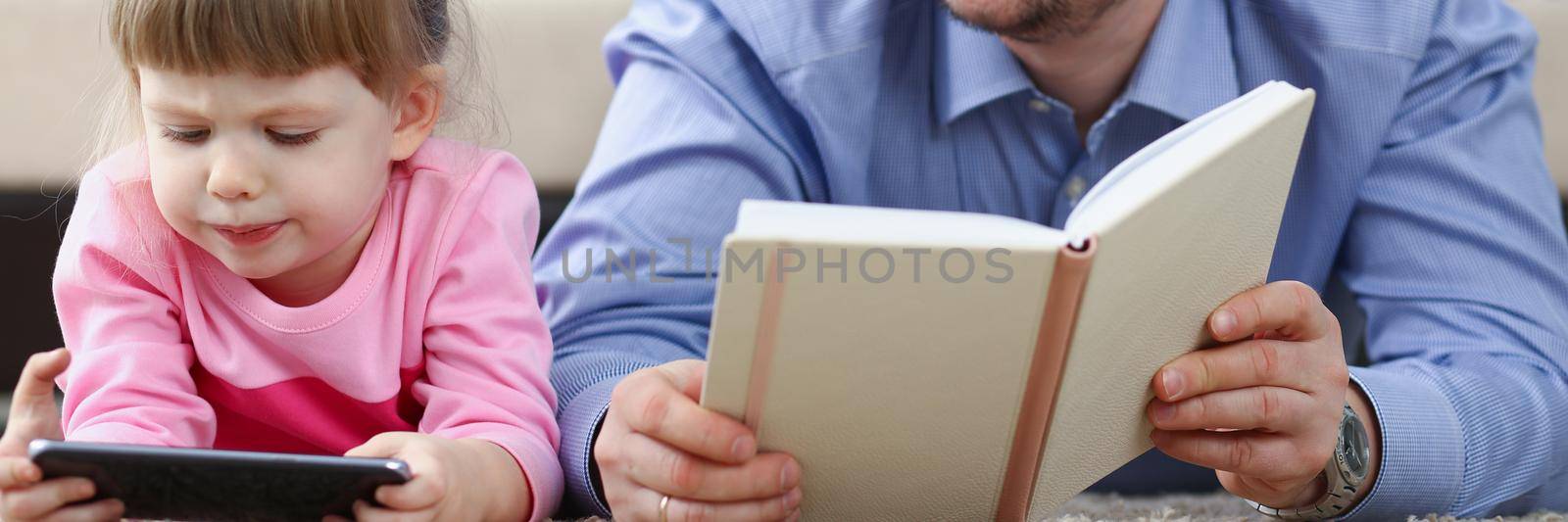 Father reading book to daughter while child stare at smartphone by kuprevich