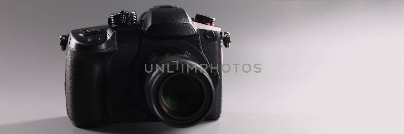 Closeup of black professional camera on gray background. Sale of photographic equipment concept