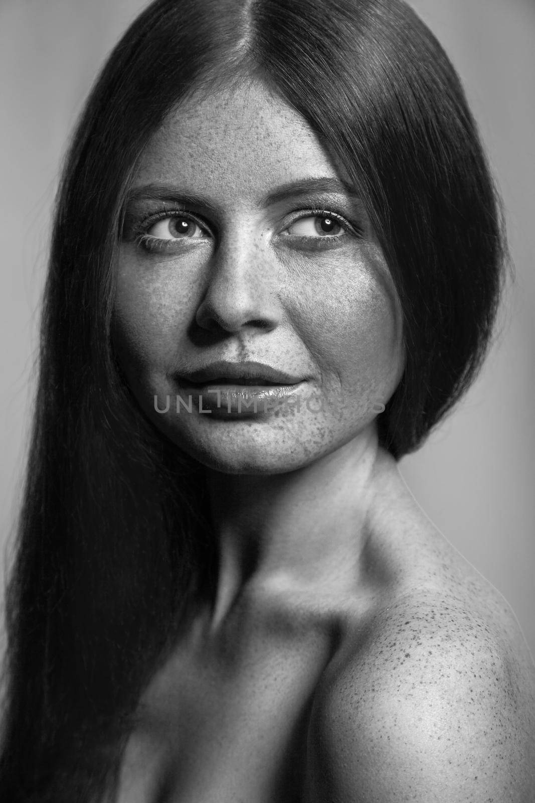 Beautiful fashion model with freckles, makeup and dark hairstyle. .Black and white photography.