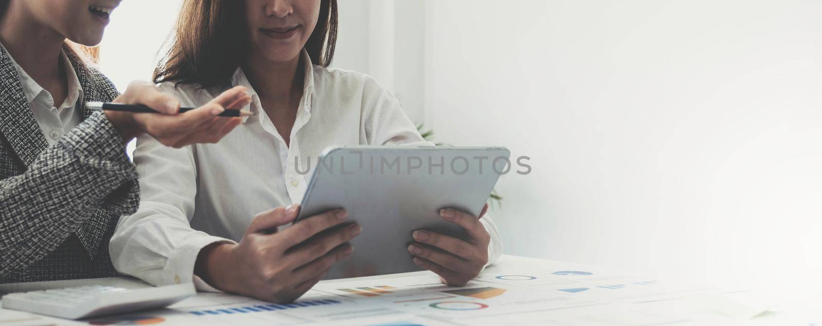 Two beautiful young asian businesswoman working together using digital tablet at office..