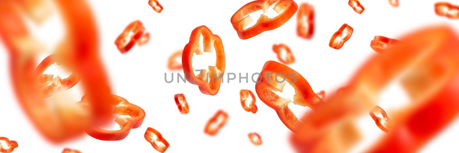 Red bell pepper cut into slices isolated on white background. Falling pepper slices in different sizes and with different directions