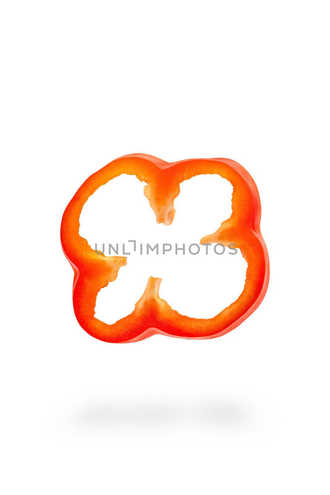 A slice of red paprika falls on a white backdrop. Red bell pepper flying in air on isolated white background.