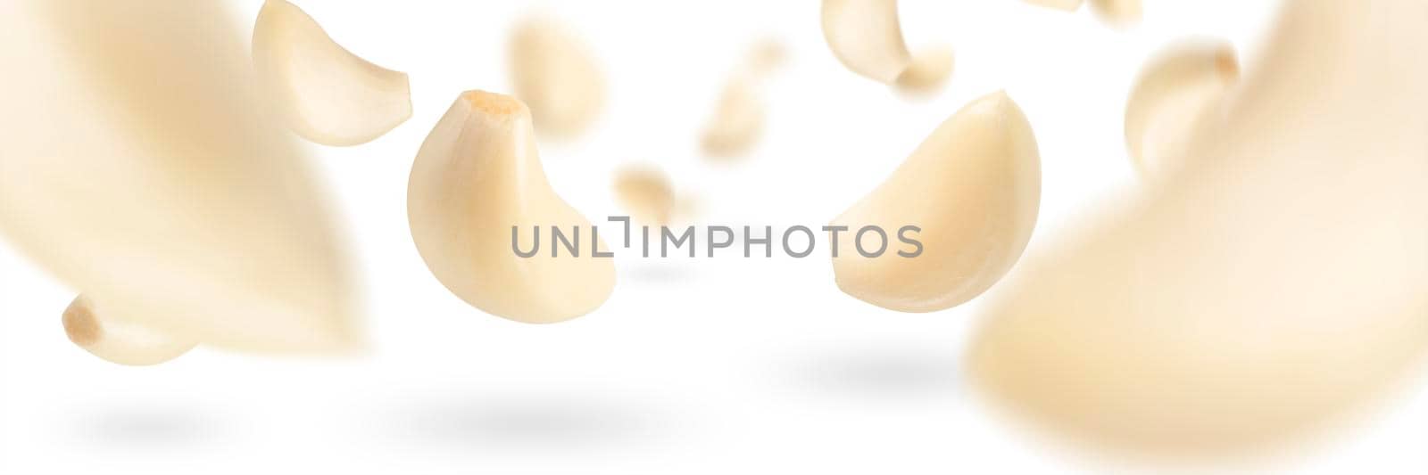 Set of peeled garlic cloves falling on a white background with selective focus. Garlic, isolated on a white background, flies down, casting a shadow. by SERSOL