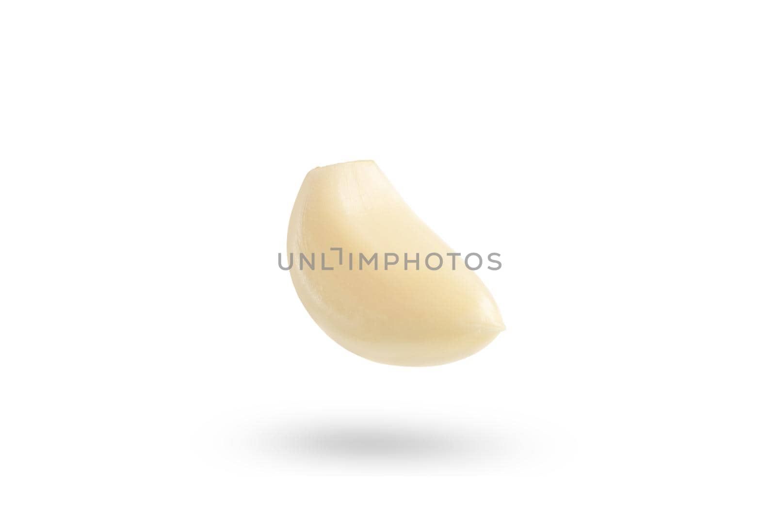 Garlic on a white background. Falling peeled clove of garlic falling on white isolated background casting shadow.