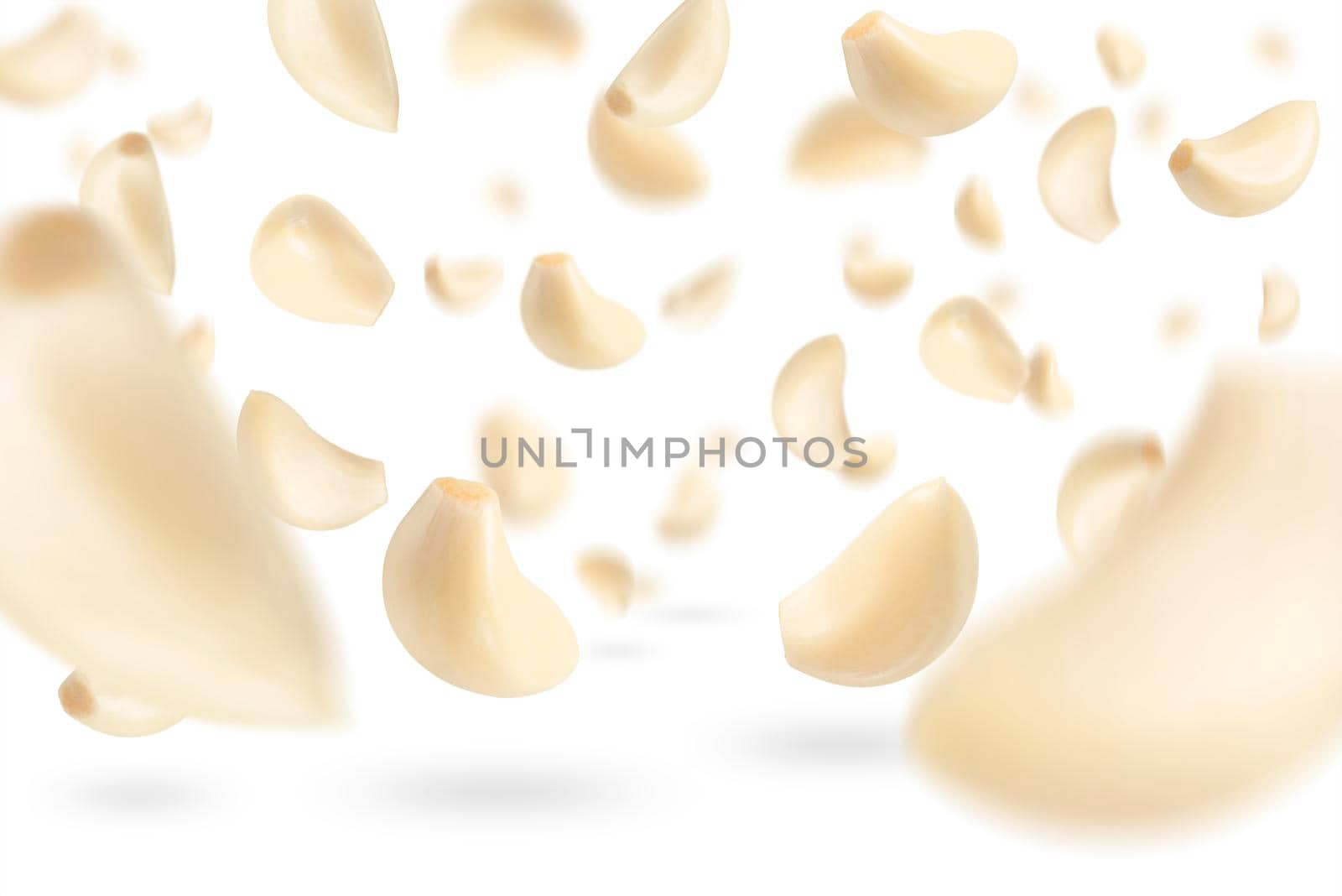Set of peeled garlic cloves falling on a white background with selective focus. Garlic, isolated on a white background, flies down, casting a shadow