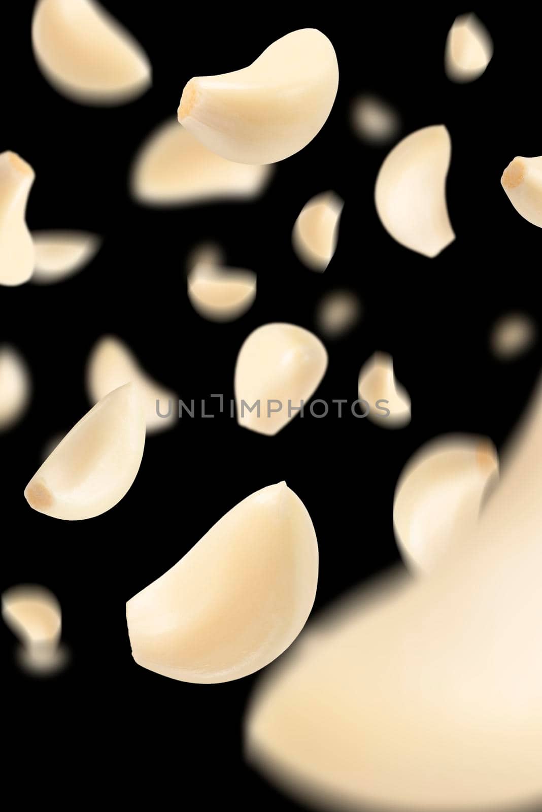 Set of peeled garlic cloves falling on a black background with selective focus. Garlic, isolated on a black background, flies down, casting a shadow