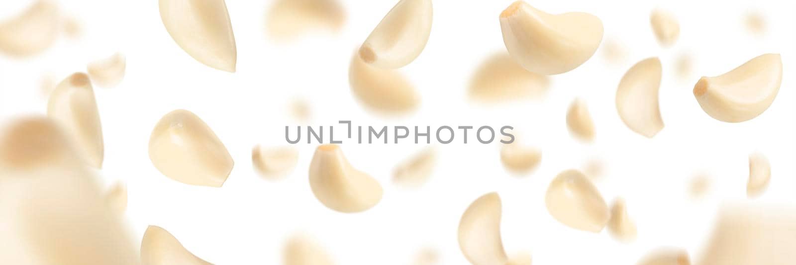 Set of peeled garlic cloves falling on a white background with selective focus. Garlic, isolated on a white background, flies down, casting a shadow