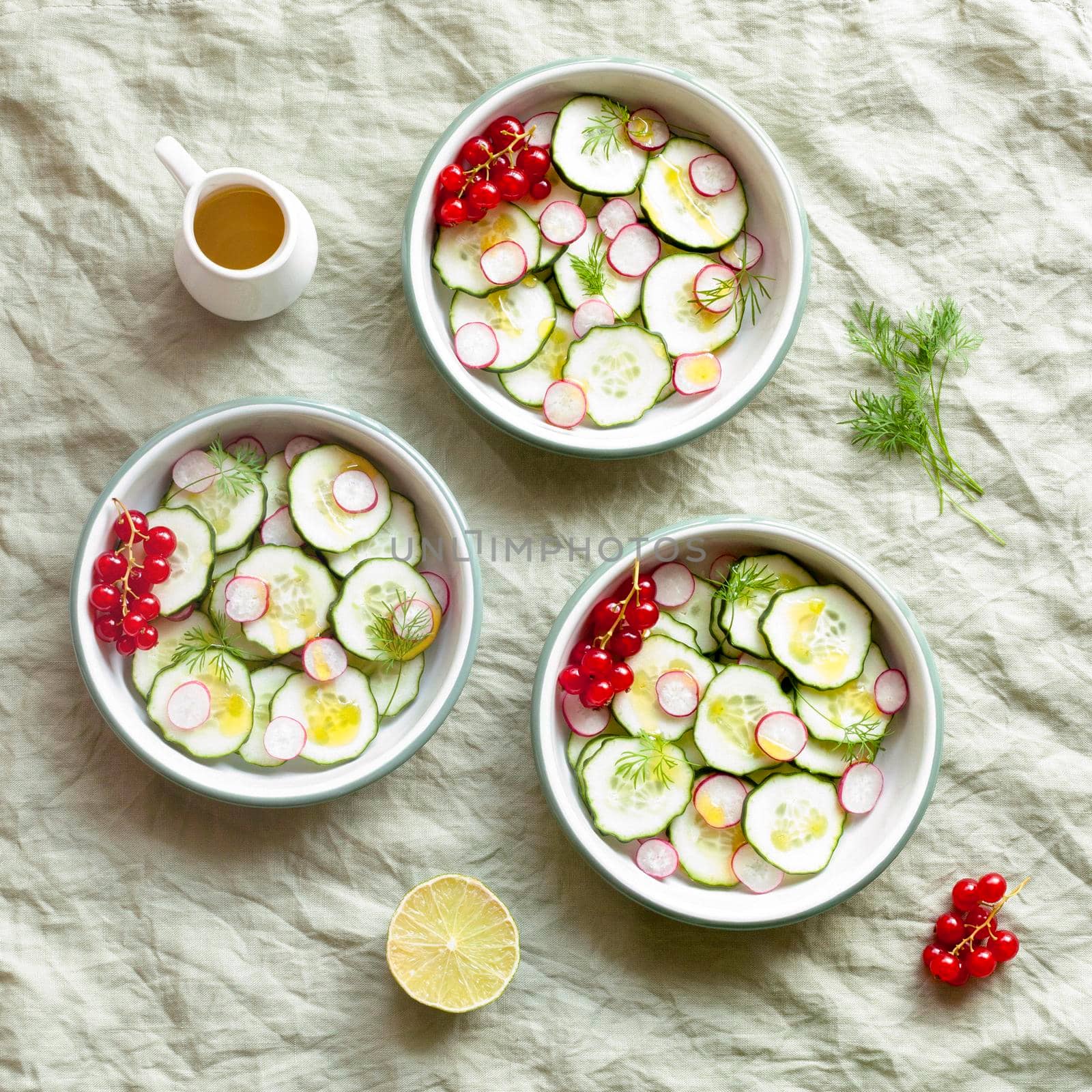radish and cucumber salad served in three round bowls, decorated with red currants, top view