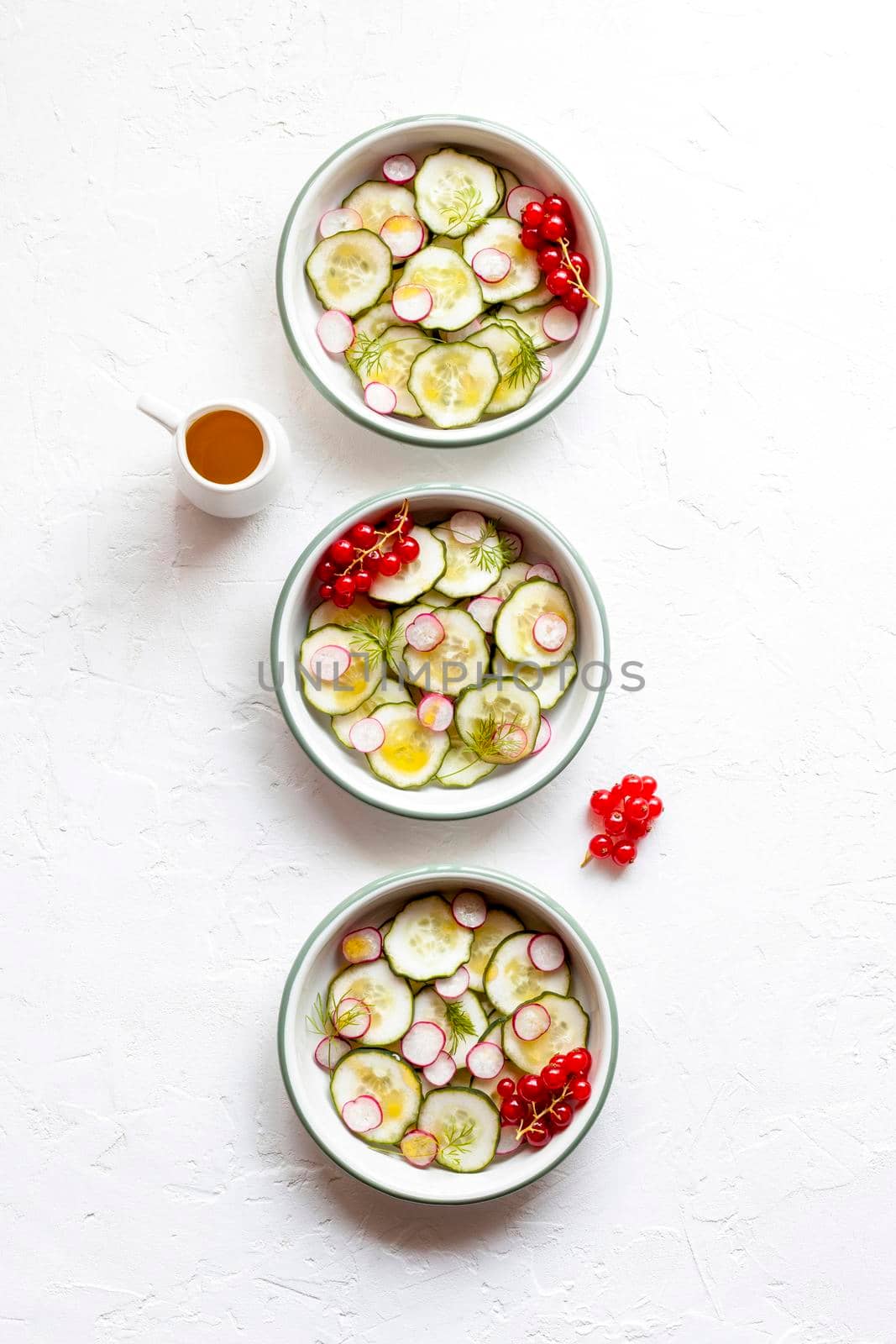cucumber and radish cold salad served in three bowls and decorated with dill and red currants, top view