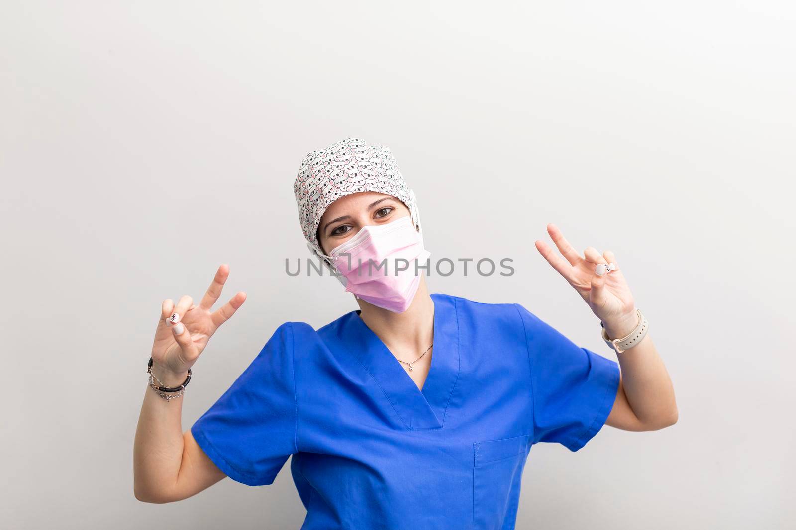 Portrait of a white dentist woman posing for the camera, and making a gesture with her hands after a day of work at the dental clinic hall